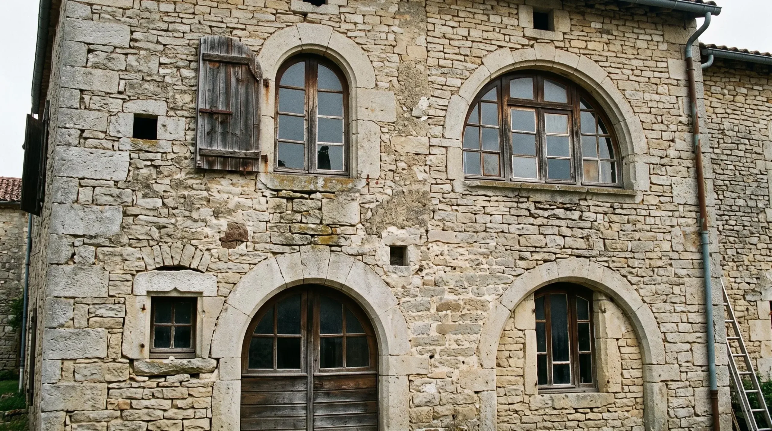 Façade de maison ancienne française présentant des ouvertures cintrées aux dimensions non-standard nécessitant des menuiseries sur mesure